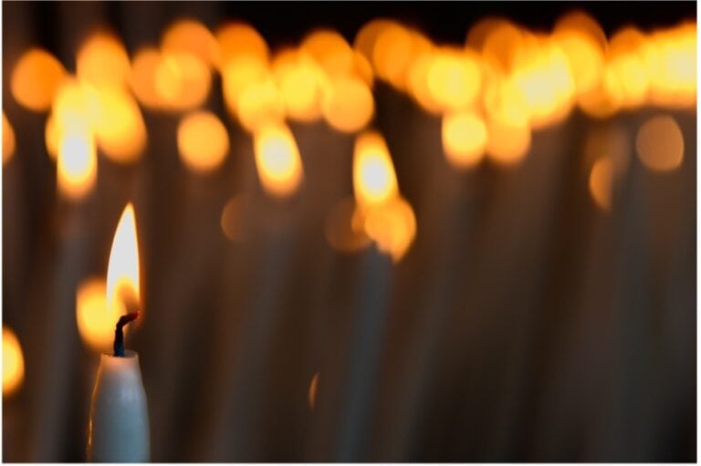 a lit candle with many candles in the background