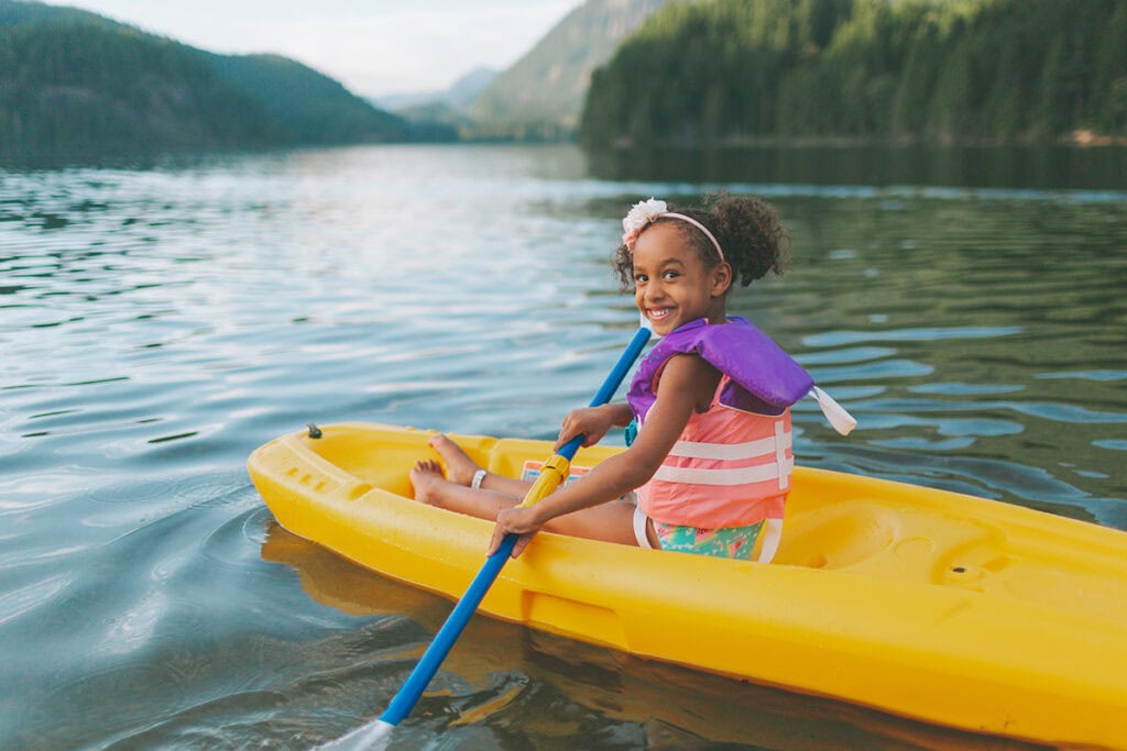 a girl in a yellow kayak on a lake