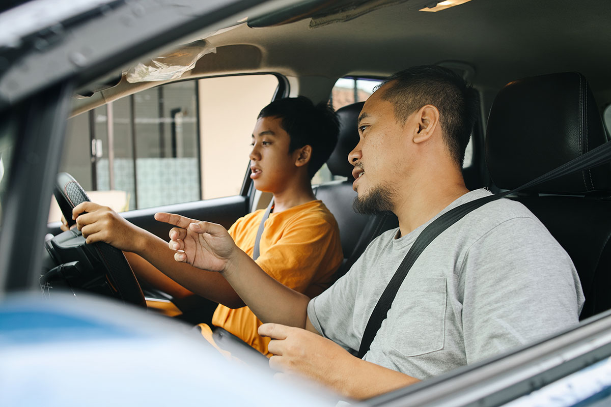 father teaching teenage son to driving a car
