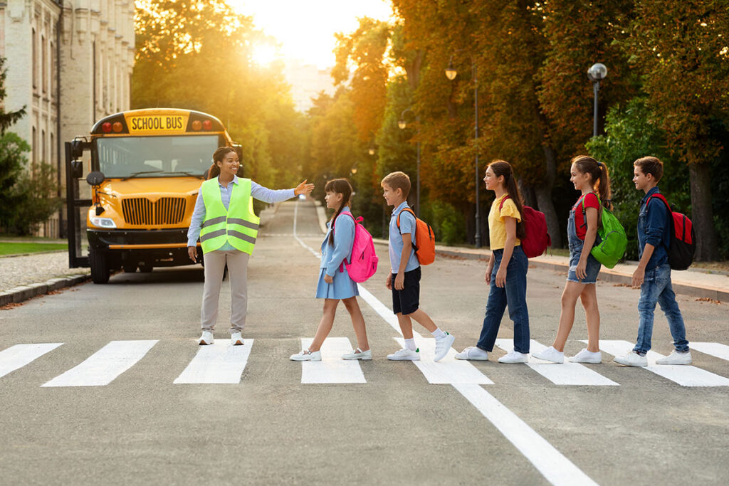 road traffic safety school bus assistant helping students cross the road