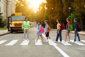 road traffic safety school bus assistant helping students cross the road