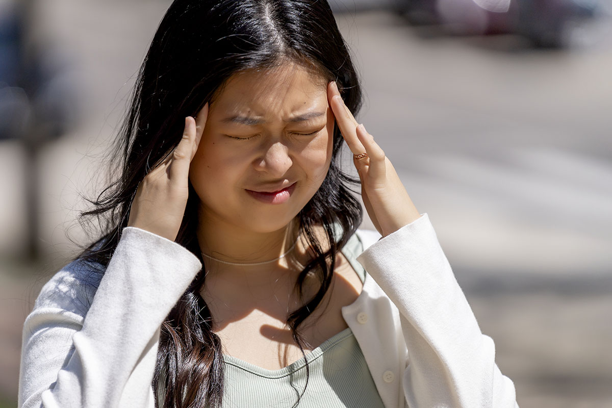 single woman suffering from headache outside in the middle of the day