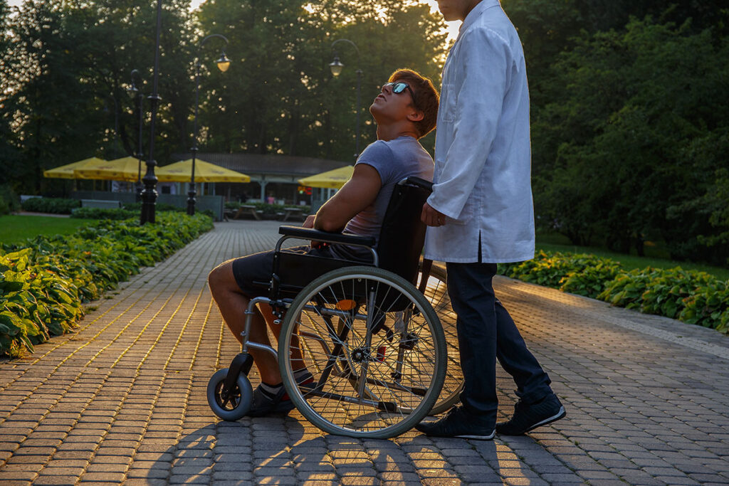 young man in wheelchair and his doctor outside