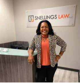 A woman in a leopard-print jacket standing at the Snellings Law front desk