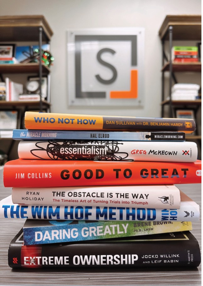 A stack of business books, including Good to Great and Extreme Ownership, in front of the Snellings Law logo