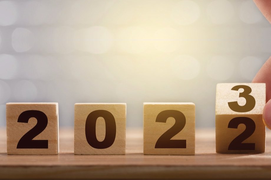 Wooden blocks spelling 2022, with a hand turning the last block to 3 for 2023