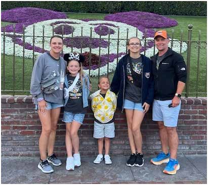A family of five posing in front of a flower display at a theme park