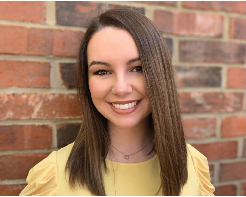Marketing assistant Erin smiling in front of a brick wall