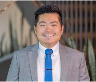 Ray Chow smiling in a gray suit and blue tie