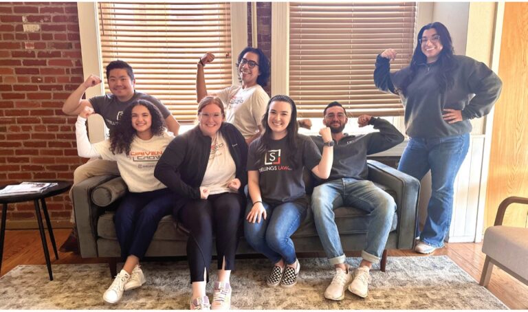 The Snellings Law staff flexing their arms together on and around a couch