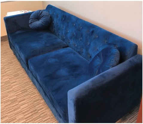 A tufted blue velvet couch in an office