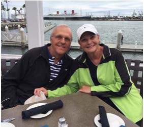 A smiling older couple seated at a waterfront restaurant table