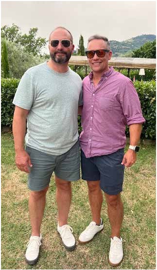 Two men in sunglasses posing together on a lawn