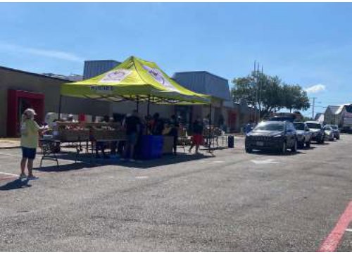 A canopy tent set up for a community event in a parking lot