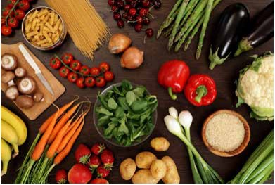 Fresh vegetables, fruit, pasta and grains spread across a table